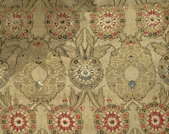 Può includere: Un tessuto intrecciato con un motivo ripetitivo di disegni floreali circolari in rosso, nero e bianco, intervallati da forme di foglie verde oliva più grandi e complesse texture a griglia geometrica sullo sfondo.