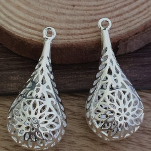 Puede incluir: Dos colgantes de filigrana de plata en forma de lágrima con un delicado diseño floral.