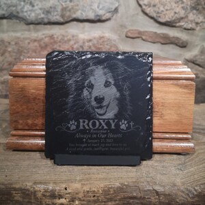Może przedstawiać: Kwadratowa czarna tablica pamiątkowa z łupka z wygrawerowanym portretem psa. Tekst zawiera napis ROXY, Roxanne, Always in Our Hearts, January 27, 2023 oraz dedykację. Tablica ma surowe krawędzie i stoi na małej podstawce.
