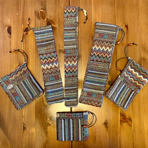 May include: Six colourful fabric pouches with drawstrings. The pouches are made of a woven fabric with a geometric pattern in shades of brown, blue, and red. The pouches are arranged in a semi-circle on a wooden surface.