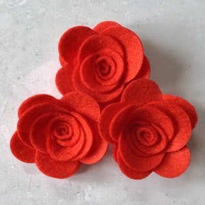 May include: Three red felt roses, each with multiple layers of petals, arranged in a cluster.