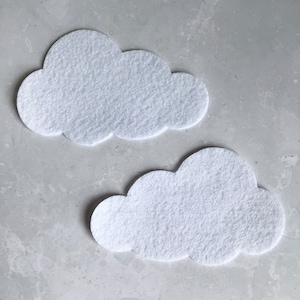 May include: Two white felt clouds, cut out in a simple shape, on a gray background.