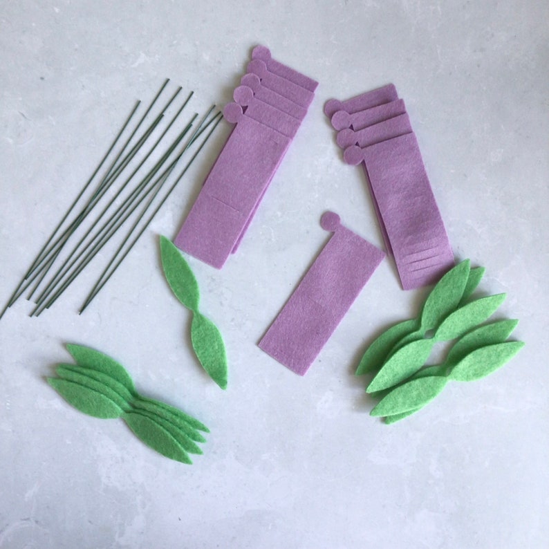May include: A set of craft supplies for making felt flowers. The set includes purple felt pieces, green felt leaves, and thin wire stems.