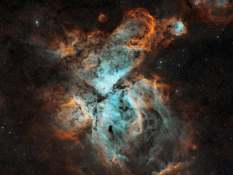 May include: A vibrant nebula featuring swirling clouds of bright cyan and deep orange gas set against a dark, star-filled space background. The gaseous structures form intricate, flowing patterns with dense, dark patches.