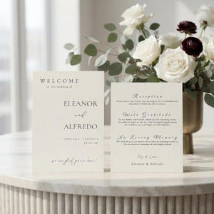 Può includere: Due cartoncini color crema per partecipazioni di nozze con testo nero in caratteri serif e corsivo. La carta a sinistra riporta Welcome to the wedding of Eleanor and Alfredo, Chicago, Illinois, 28.07.28. La destra dettaglia ricevimento e ringraziamenti.