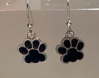 May include: A pair of silver dangle earrings with black paw print charms.