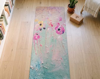 May include: A rectangular yoga mat featuring an abstract watercolor-style print with a soft palette of mint green, pale pink, and yellow. The design includes scattered floral-like shapes and paint splatters across the surface.