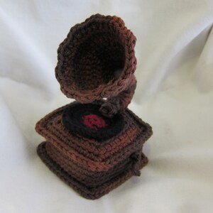 May include: A crocheted brown and black gramophone with a red record.