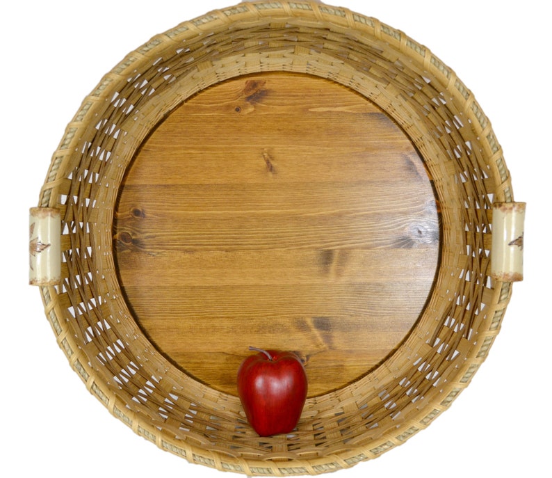 Pu&ograve; includere: Un cesto rotondo intrecciato con una base in legno e una mela rossa all'interno. Il cesto &egrave; fatto di materiali naturali e ha un aspetto rustico.