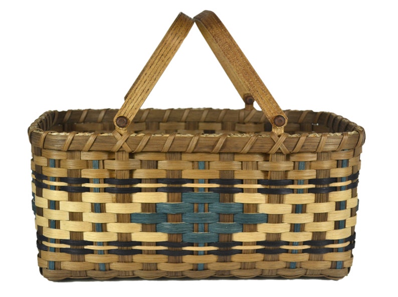 May include: A woven basket with a rectangular shape and a brown, black, and blue pattern. The basket has two wooden handles.