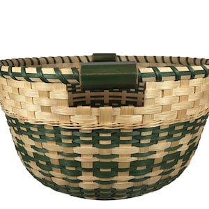 May include: A woven basket with a green and natural colored pattern. The basket has a green wooden handle.