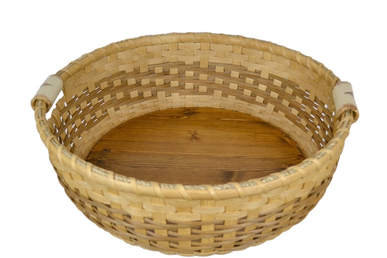 Pu&ograve; includere: Un cesto intrecciato con una base in legno e due manici. Il cesto &egrave; fatto di materiali naturali e ha un colore marrone chiaro.