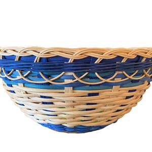 May include: A woven basket with a blue and green pattern. The basket is made of natural materials and has a round shape.