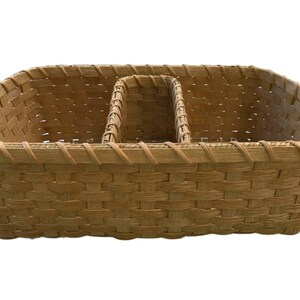 May include: A woven wicker basket with three divided sections. The basket is light brown and has a woven pattern.