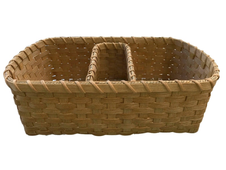 May include: A woven wicker basket with three divided sections. The basket is light brown and has a woven pattern.