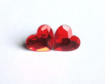 May include: Two red heart-shaped rhinestones. The rhinestones are faceted and have a shiny finish.