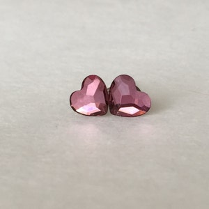 May include: A pair of pink heart-shaped earrings with a faceted design.