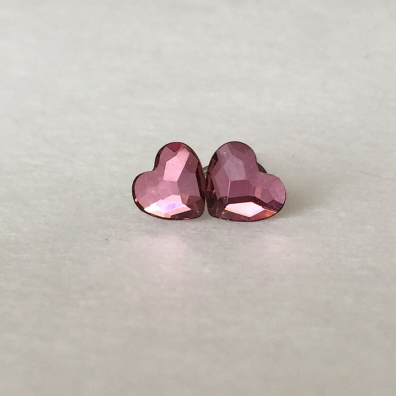 May include: A pair of pink heart-shaped earrings with a faceted design.