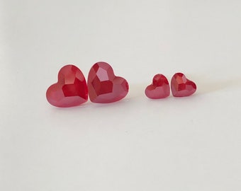 May include: Four red heart-shaped rhinestones, two larger and two smaller.