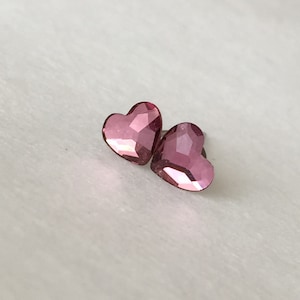 May include: A pair of pink heart-shaped earrings with a faceted finish.