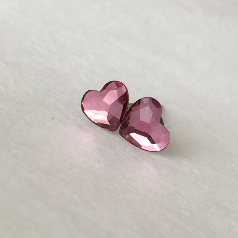 May include: A pair of pink heart-shaped earrings with a faceted finish.