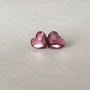 May include: A pair of pink heart-shaped earrings with a faceted design.