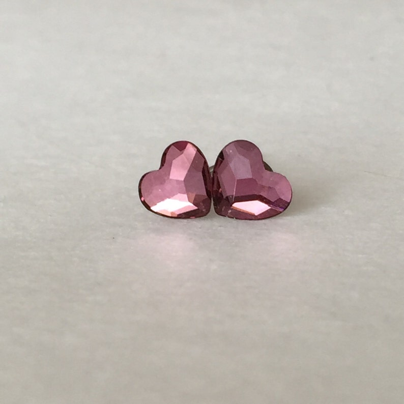 May include: A pair of pink heart-shaped earrings with a faceted design.