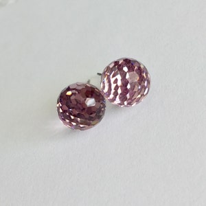 May include: A pair of pink crystal stud earrings with a faceted design.