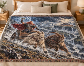 May include: A woven throw blanket featuring a detailed illustration of a red-haired figure in armor holding a hammer while riding in a wooden chariot pulled by two large, shaggy goats across a rocky, mountainous landscape with a stormy sky.