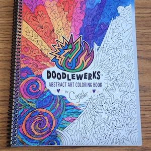May include: A spiral-bound coloring book titled Doodlewerks Abstract Art Coloring Book by Carol Jean. The cover features a vibrant, multi-colored abstract design with hearts, swirls, and stars, transitioning from a fully colored left side to an uncolored line art right side.
