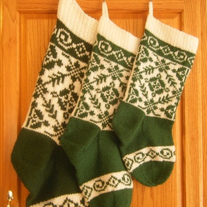 Pode incluir: Três meias de Natal de malha verde e branca penduradas em uma porta de armário de madeira.