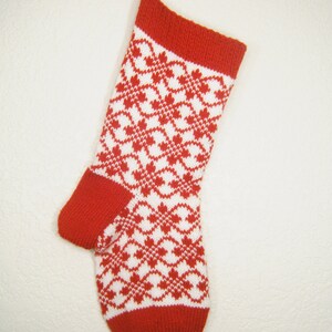 May include: Red and white knitted Christmas stocking with a geometric pattern.