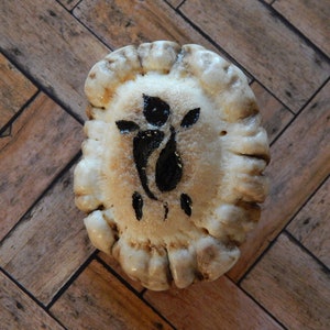 May include: A white antler with a black floral design painted on it. The antler is round and has a textured surface.