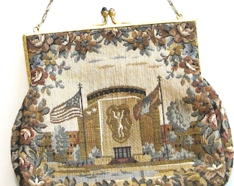 May include: Vintage tapestry handbag with a gold chain strap. The bag features a detailed woven design of a building with flags, likely a historical landmark. Floral patterns frame the central image, with a gold clasp closure.