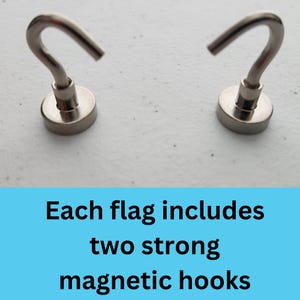 May include: Two silver magnetic hooks with a hook shape on top. Each hook has a round base. The text "Each flag includes two strong magnetic hooks" is below the hooks.