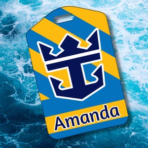 May include: A personalized luggage tag with a blue and yellow striped background. The tag features a navy blue anchor and crown logo with the name "Amanda" in white lettering. The tag has a hole at the top for attachment.