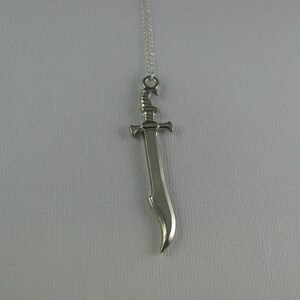 May include: A silver sword pendant necklace. The sword has a curved blade and a detailed hilt.