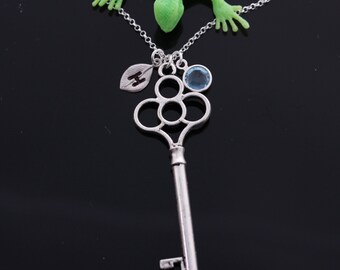 May include: A silver key necklace with a blue gemstone and a leaf charm with the letter H engraved on it.