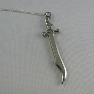 May include: A silver sword pendant necklace. The sword has a curved blade and a detailed hilt.