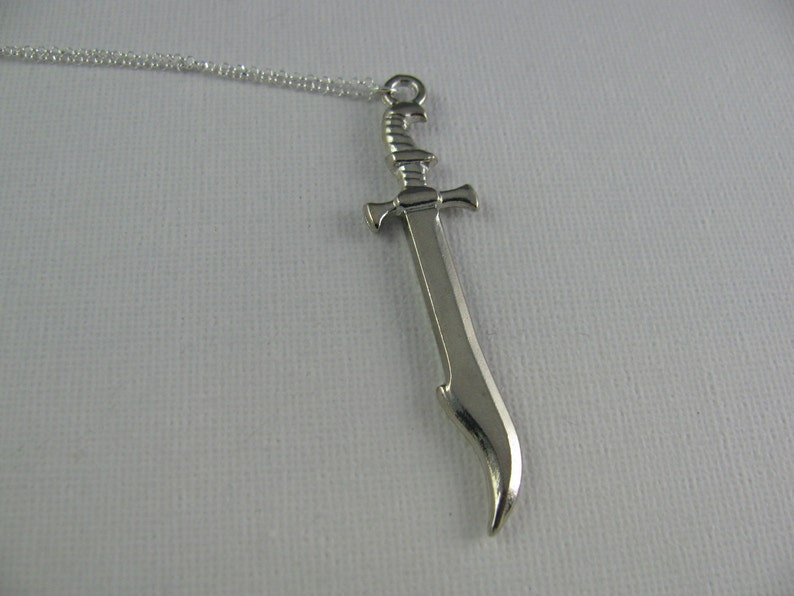 May include: A silver sword pendant necklace. The sword has a curved blade and a detailed hilt.