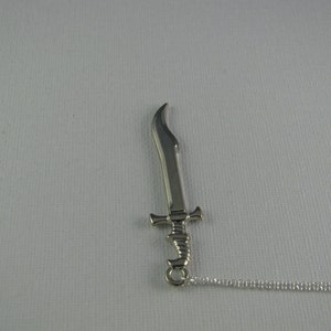 May include: A silver sword pendant necklace with a chain. The sword has a curved blade and a detailed hilt.