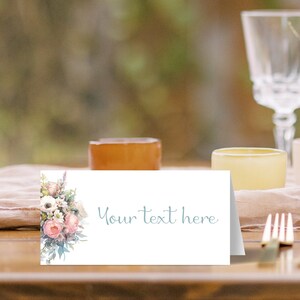May include: A white place card with a floral design on the left side. The text "Your text here" is printed in light blue on the right side.