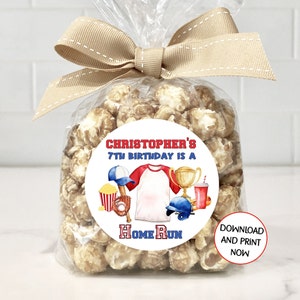 May include: A white circle sticker with a baseball theme. It says "Christopher's 7th Birthday is a Home Run" with a baseball bat, glove, hat, trophy, popcorn, and a drink. The sticker is on a clear plastic bag filled with popcorn.