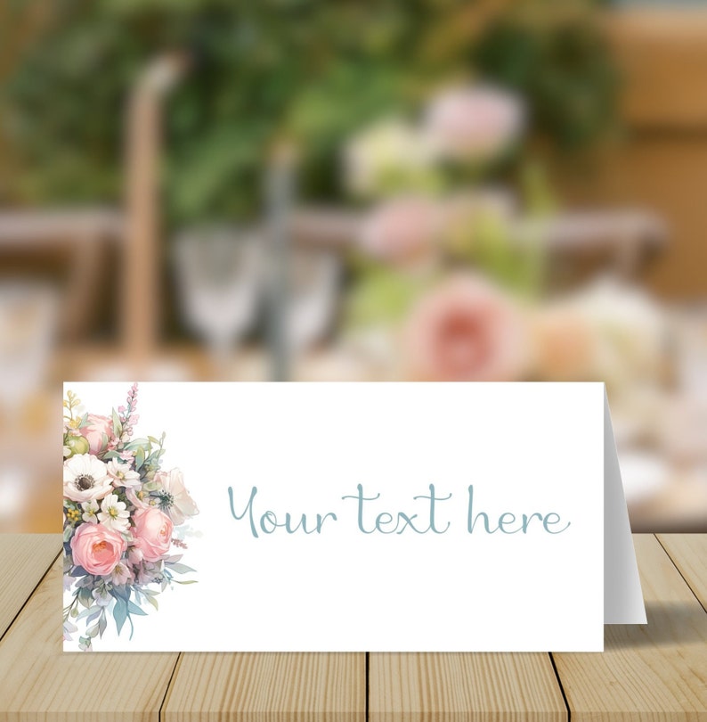 May include: A white place card with a floral design on the left side and the text "Your text here" in blue script on the right side.