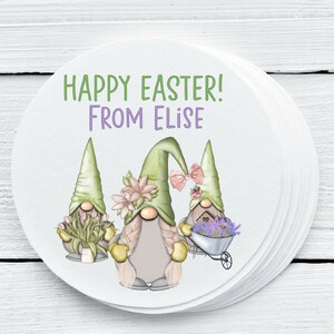 May include: A pile of circular white stickers with an Easter-themed illustration. The design shows three gnomes with green hats and flowers, and the text "HAPPY EASTER! FROM ELISE" in green and purple.