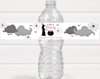 May include: Water bottle label with a witch silhouette, a cauldron, and bats. The text reads "A baby is brewing" and "Elizabeth's Baby Shower".
