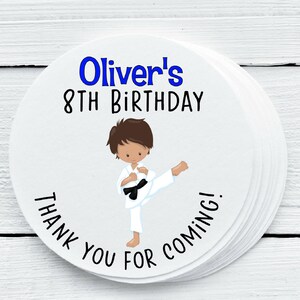 Puede incluir: Etiqueta redonda blanca con texto azul que dice "Oliver's 8th Birthday" y texto negro que dice "¡Gracias por venir!" Una ilustración de dibujos animados de un niño con un uniforme de karate blanco con cinturón negro está en el centro de la etiqueta.