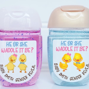 May include: Two clear plastic bottles with pink and blue glitter inside. Each bottle has a sticker with a cartoon duck couple and the text "He or She Waddle It Be? Baby Smith Gender Reveal".