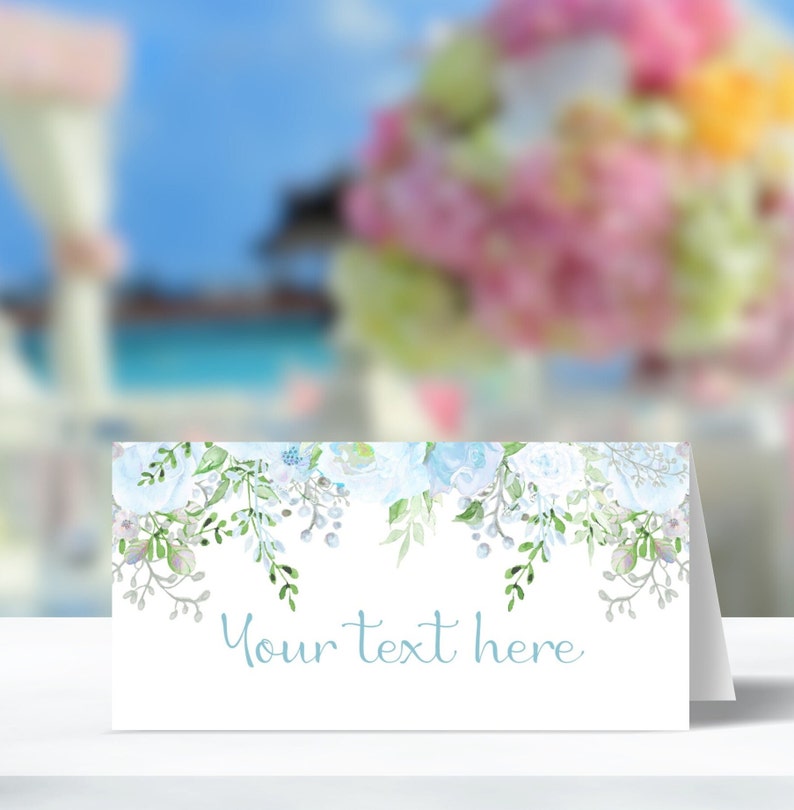 May include: White place card with a blue watercolour floral border and the text "Your text here" in blue.