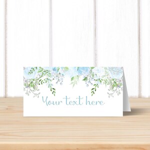 May include: White place card with a blue floral border and the text "Your text here" in blue.